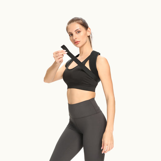 Woman adjusting the crossed straps of a black posture corrector belt, front view