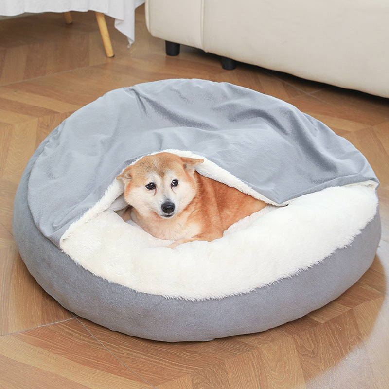 Shiba dog lying under the hood of a gray round hooded dog bed